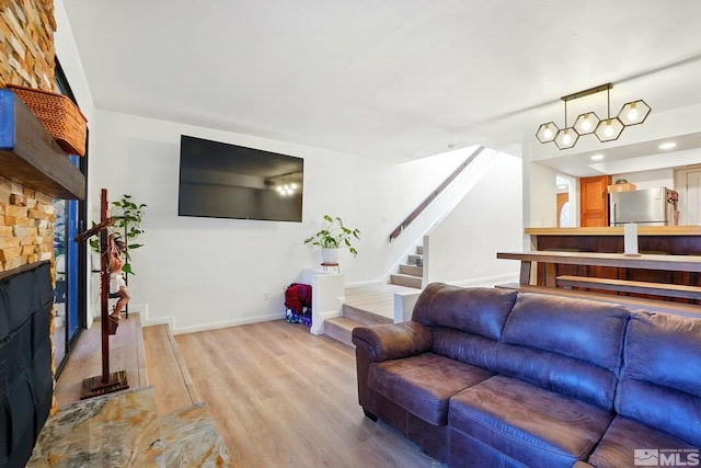 living room featuring baseboards, light wood-type flooring, and stairs