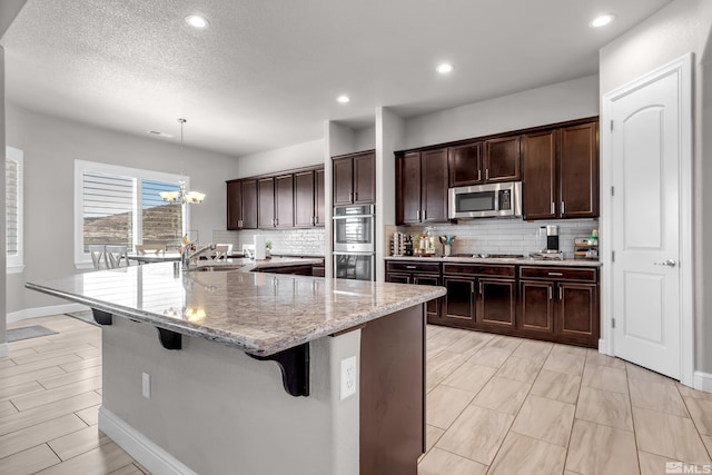 kitchen featuring a sink, a kitchen breakfast bar, backsplash, and stainless steel appliances