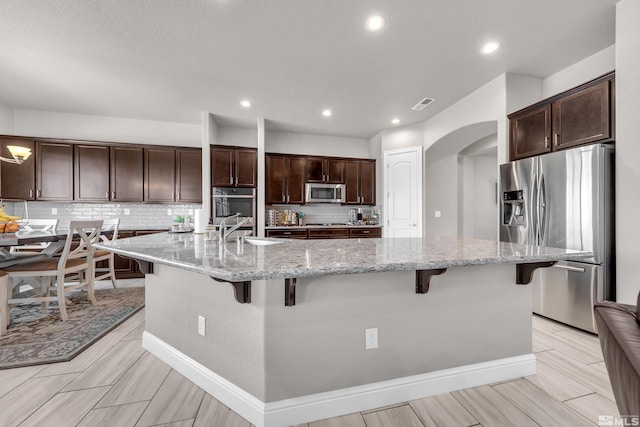 kitchen featuring visible vents, arched walkways, appliances with stainless steel finishes, and dark brown cabinetry