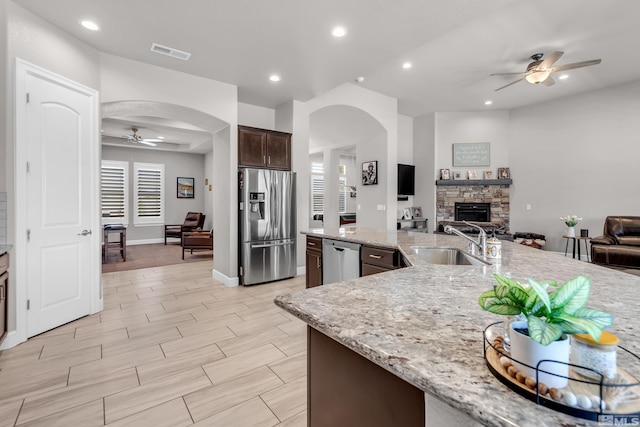 kitchen featuring a ceiling fan, visible vents, a sink, open floor plan, and stainless steel appliances
