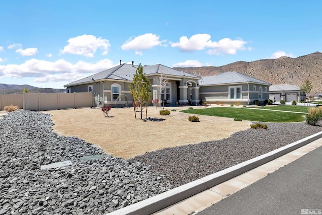 view of front of house featuring fence, a mountain view, stucco siding, and a front yard