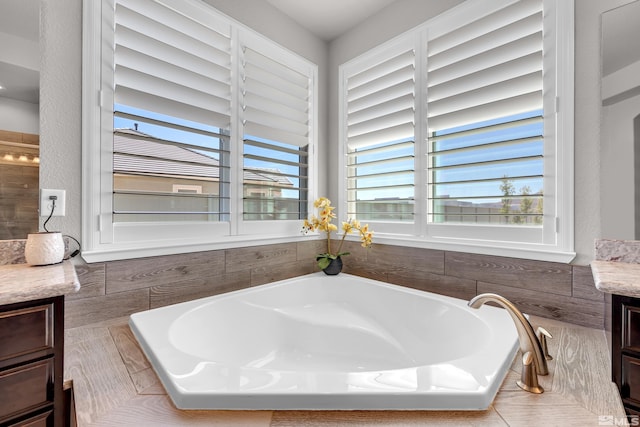 full bath with a healthy amount of sunlight, vanity, and a garden tub