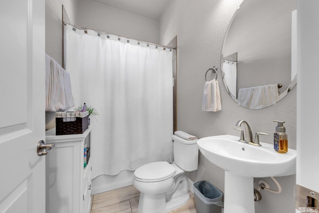 bathroom featuring shower / bath combo with shower curtain, a sink, and toilet