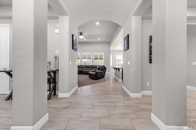 corridor with baseboards, recessed lighting, and arched walkways