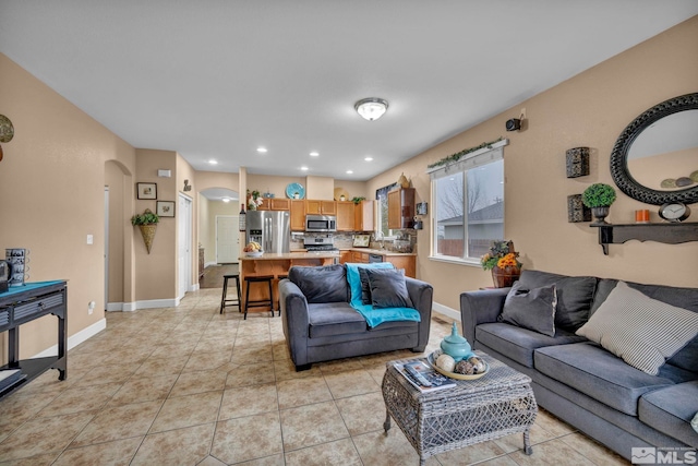 living area with baseboards, arched walkways, light tile patterned floors, and recessed lighting