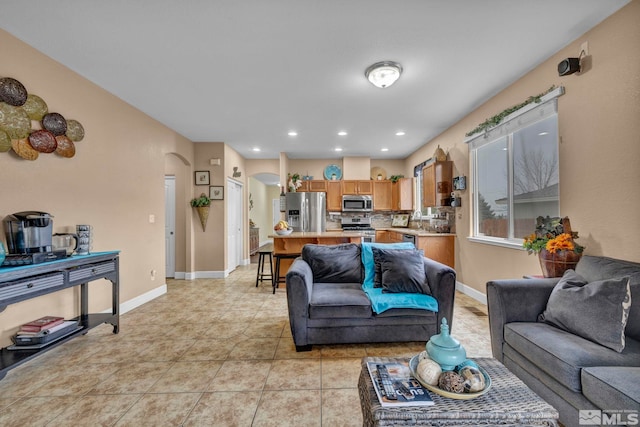 living area with recessed lighting, arched walkways, baseboards, and light tile patterned floors