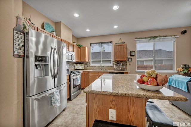 kitchen with appliances with stainless steel finishes, tasteful backsplash, light stone countertops, light tile patterned floors, and recessed lighting