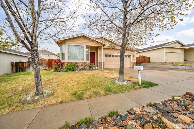 view of front of property with fence, a front yard, stone siding, concrete driveway, and an attached garage