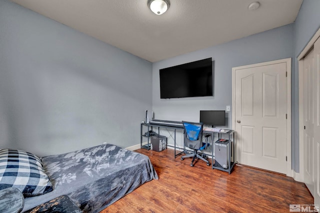 bedroom with baseboards, a closet, and wood finished floors