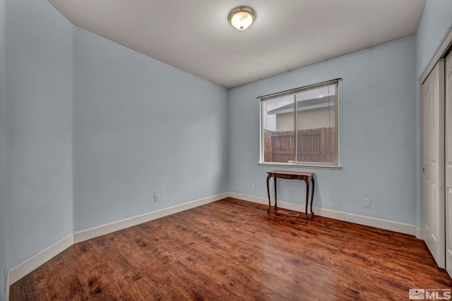 unfurnished bedroom with baseboards, a closet, and wood finished floors
