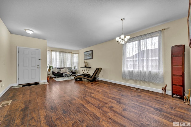 sitting room featuring a chandelier, a wealth of natural light, visible vents, and wood finished floors