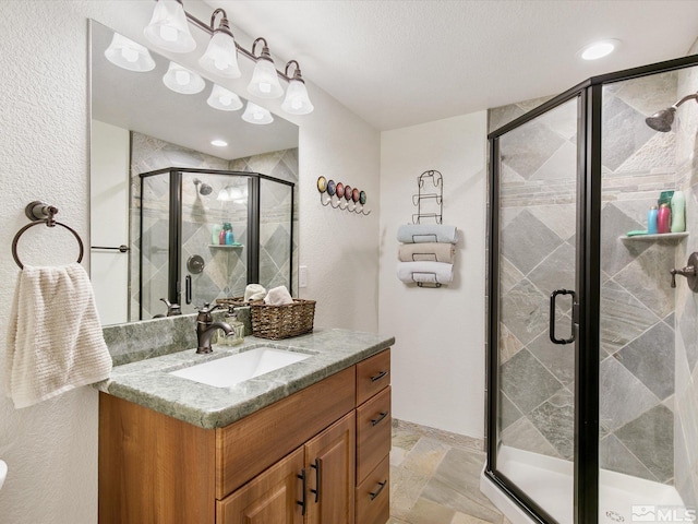 bathroom featuring vanity, a textured wall, a stall shower, and stone finish floor