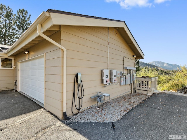 view of property exterior featuring an attached garage, driveway, and a mountain view