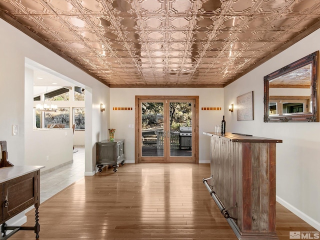 hall with french doors, an ornate ceiling, a chandelier, and hardwood / wood-style floors