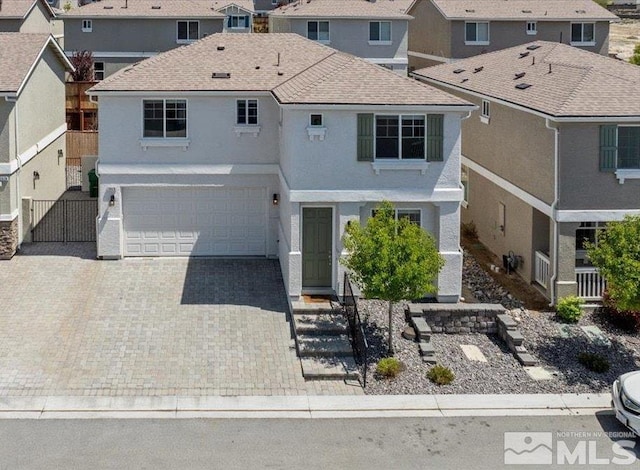 traditional-style home featuring a garage, fence, decorative driveway, stucco siding, and a residential view