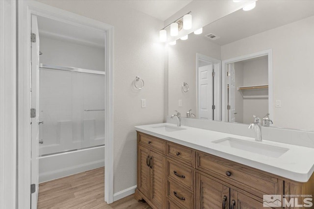 full bathroom featuring a sink, double vanity, wood finished floors, and visible vents