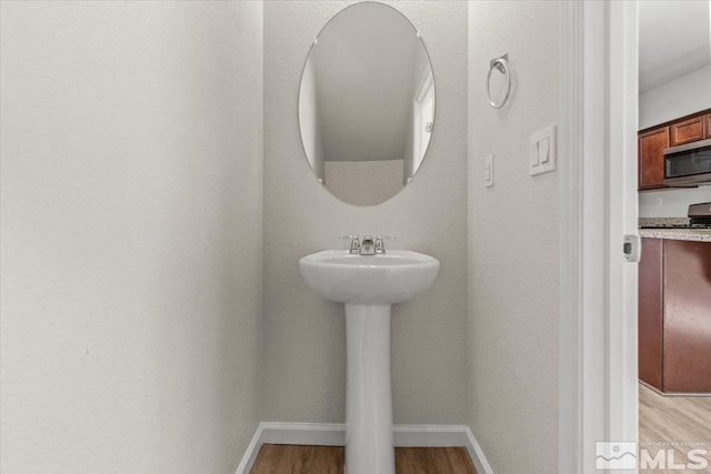 bathroom with baseboards, a sink, and wood finished floors