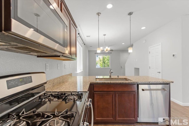 kitchen featuring a sink, light stone countertops, stainless steel appliances, and light wood finished floors