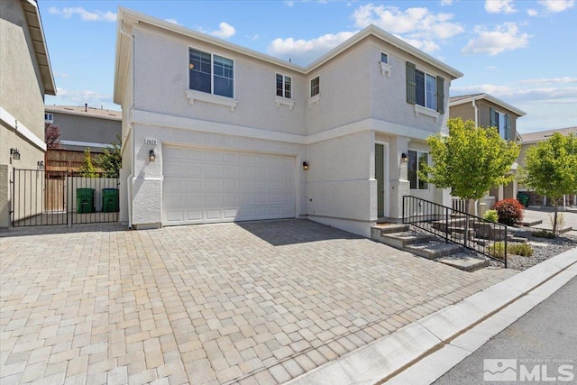 traditional-style house featuring a garage, fence, stucco siding, and decorative driveway