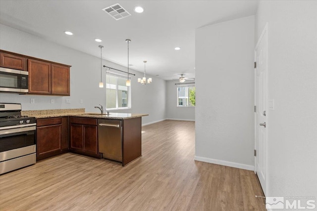 kitchen with light stone countertops, a sink, light wood-style floors, stainless steel appliances, and visible vents