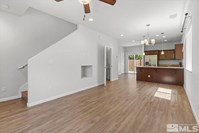 unfurnished living room featuring recessed lighting, visible vents, ceiling fan with notable chandelier, and light wood-type flooring