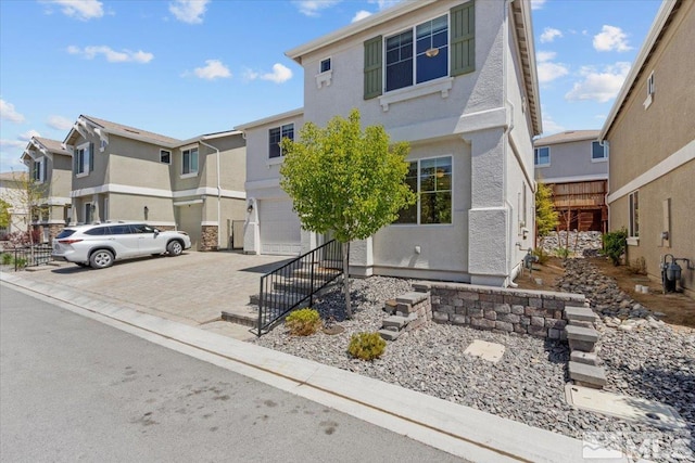 view of front of home with a residential view, stucco siding, an attached garage, and driveway