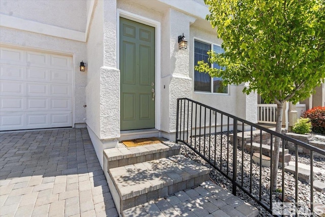 view of exterior entry featuring a garage and stucco siding