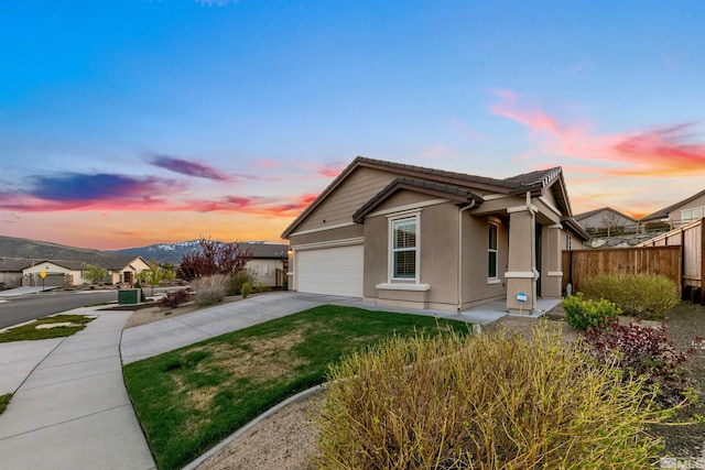 view of front of house featuring a front lawn, fence, stucco siding, concrete driveway, and an attached garage