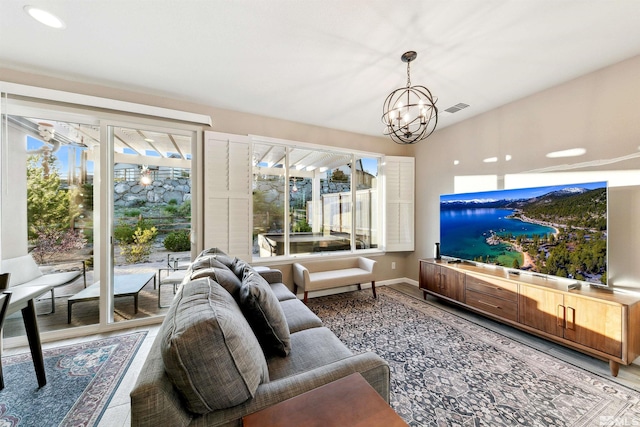 living area featuring baseboards, a chandelier, wood finished floors, and visible vents