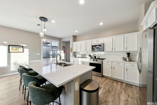 kitchen featuring a sink, white cabinetry, appliances with stainless steel finishes, and light wood-style flooring