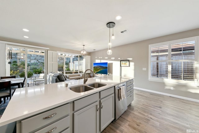 kitchen with visible vents, decorative light fixtures, dishwasher, a sink, and light wood finished floors