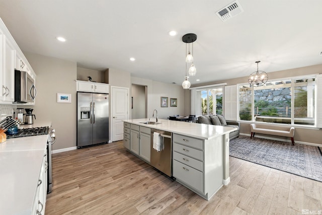 kitchen featuring appliances with stainless steel finishes, a sink, baseboards, light wood-type flooring, and visible vents