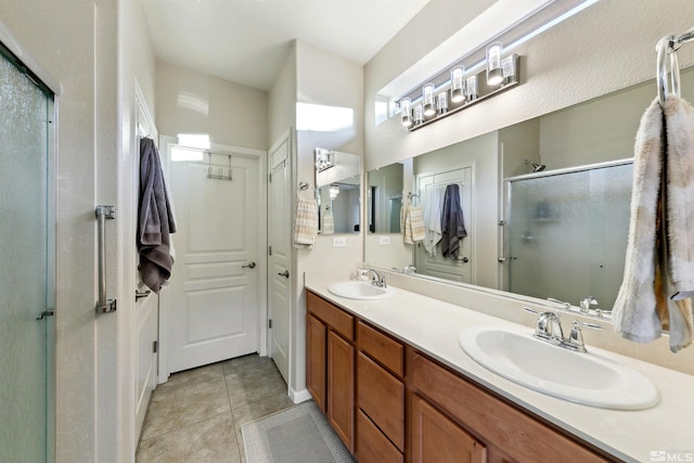 bathroom with double vanity, a sink, a stall shower, and tile patterned floors