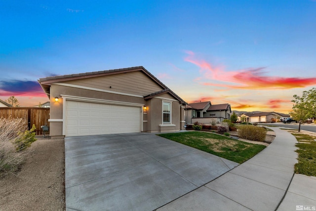 ranch-style house featuring driveway, a front yard, fence, an attached garage, and stucco siding