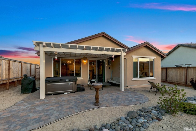 back of property with a fenced backyard, a pergola, stucco siding, and a hot tub