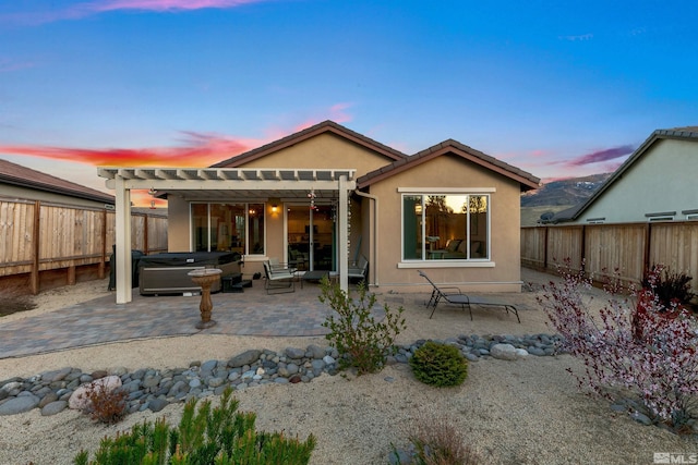 back of house featuring a pergola, a patio, a fenced backyard, stucco siding, and a hot tub