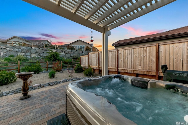 patio terrace at dusk featuring a hot tub, a pergola, and a fenced backyard