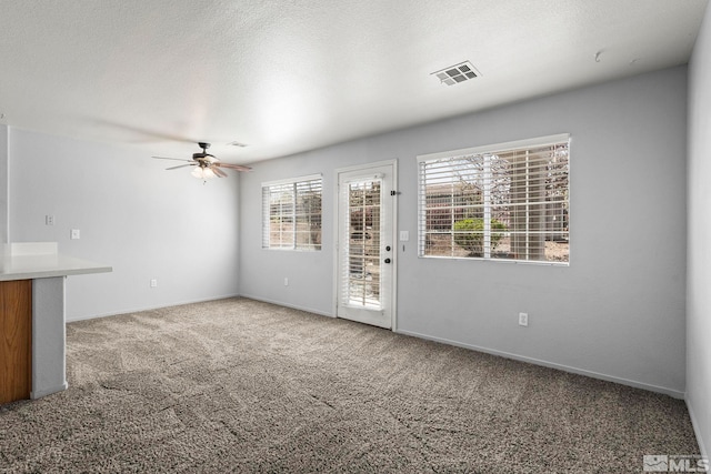 unfurnished living room featuring carpet floors, ceiling fan, baseboards, and visible vents