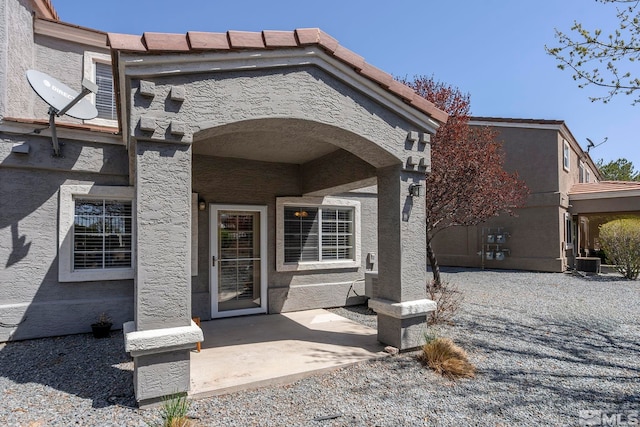 doorway to property with a patio, stucco siding, and cooling unit