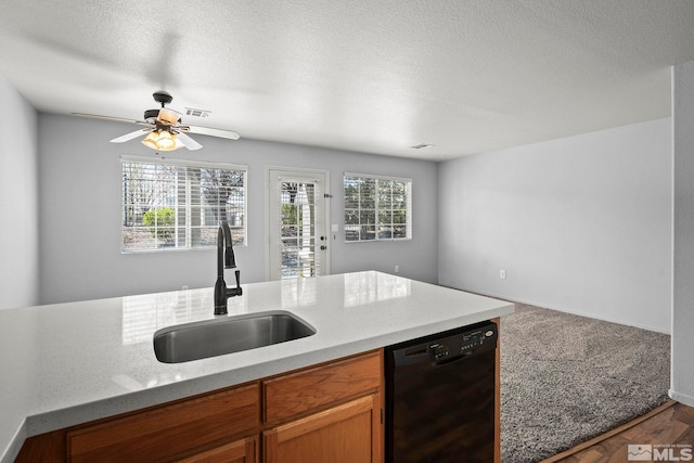 kitchen featuring brown cabinets, a sink, black dishwasher, a ceiling fan, and visible vents