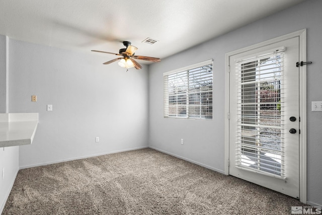 empty room with ceiling fan, visible vents, baseboards, and carpet