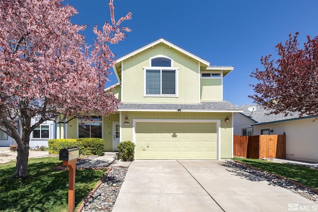 traditional-style house featuring fence, a shingled roof, driveway, and a garage