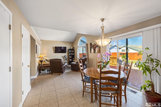 dining space with baseboards, visible vents, light tile patterned floors, and lofted ceiling
