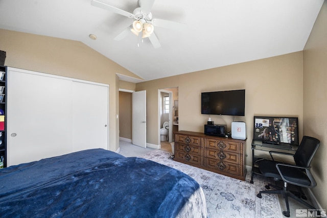carpeted bedroom with ensuite bath, a ceiling fan, baseboards, lofted ceiling, and a closet
