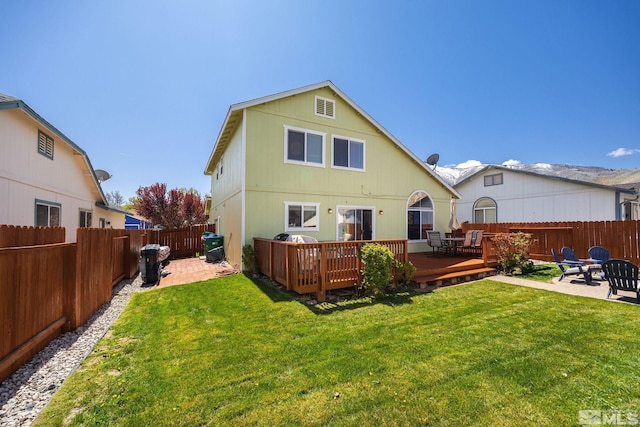rear view of house with a fenced backyard, a patio area, a yard, and a deck