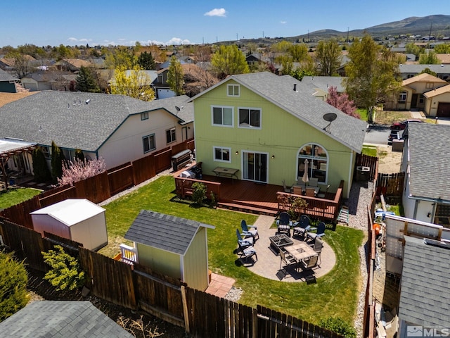 rear view of house with a fenced backyard, a shingled roof, a deck with mountain view, and a residential view
