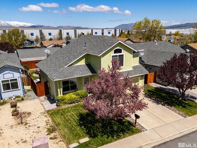 view of front of property featuring roof with shingles, fence, a residential view, a mountain view, and concrete driveway