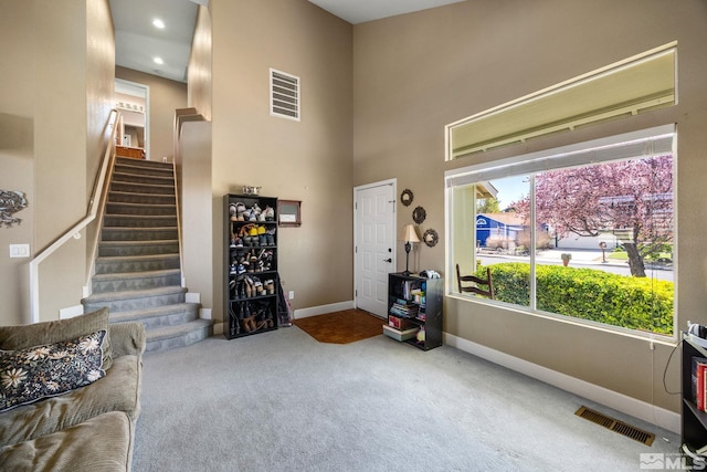 interior space featuring stairway, baseboards, a high ceiling, and visible vents
