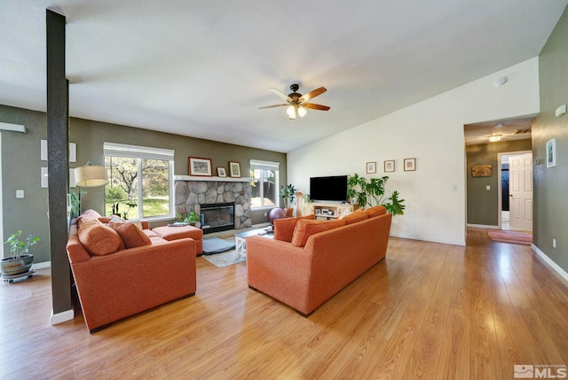living area with ceiling fan, a fireplace, light wood-style flooring, baseboards, and lofted ceiling