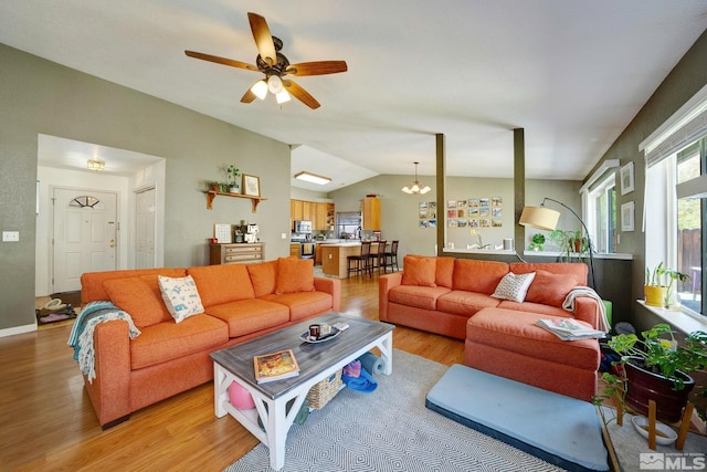 living room featuring light wood-style flooring, ceiling fan with notable chandelier, and vaulted ceiling